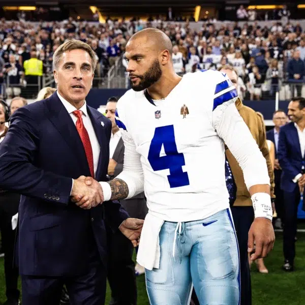 Chris Cassidy and Dallas Cowboys quarterback Dak Prescott Retired Navy SEAL and Astronaut Chris Cassidy in a professional suit shaking hands with Dallas Cowboys quarterback Dak Prescott on the field during a high-profile event.